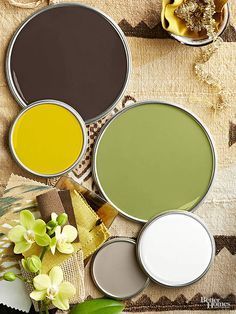 four different shades of paint sitting next to each other on top of a table with flowers