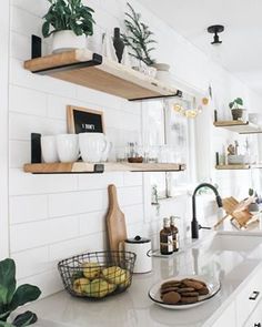 a white kitchen with open shelving above the sink and counter top, filled with dishes