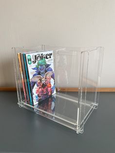 a stack of magazines sitting on top of a table next to a book holder filled with books