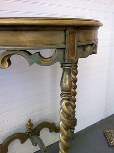 an antique wooden table with gold paint on it