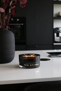 a candle that is on top of a counter next to a vase with flowers in it