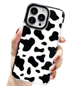 a woman's hand holding an iphone case with black and white cow print