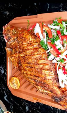 a large piece of meat sitting on top of a tray filled with veggies