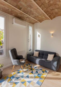 a living room filled with furniture and a rug on top of a hard wood floor