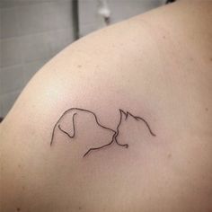 a woman's shoulder with a small tattoo of two cats kissing each other on it