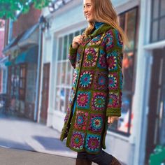 a woman is walking down the street wearing a colorful crocheted coat and boots