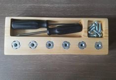 screwdrivers and nuts in a wooden holder on a table with screws attached to it