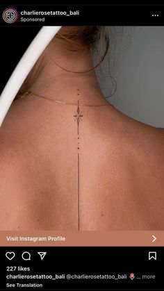 the back of a woman's neck with a cross tattoo on it