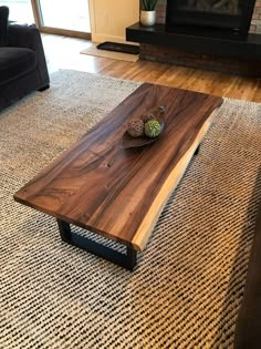 a wooden table sitting on top of a rug in front of a couch and fireplace