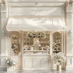 a white store front with flowers and vases on the sidewalk in front of it