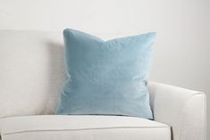 a light blue pillow sitting on top of a white couch