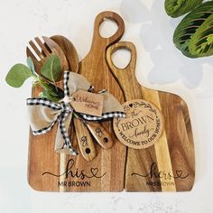 two wooden cutting boards with personalized names on them and a bow tied around the handles