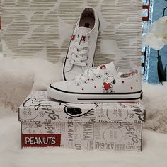 a pair of white sneakers sitting on top of a box with peanuts written on it