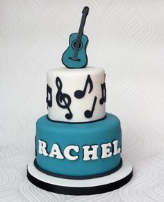 a blue and white cake with musical notes on it's top, topped with a guitar