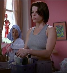 two women standing in a living room with pink walls and blue curtains on the windowsill