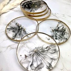 four glass plates sitting on top of a white counter covered in black and gold paint