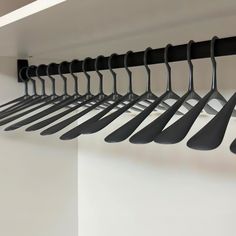 there are many black spoons hanging from the hooks on the wall in this room