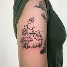 a woman's arm with mushrooms and leaves on it