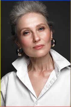 an older woman with grey hair and large hoop earrings on her head is looking at the camera