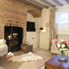 a living room filled with furniture and a fire place next to a brick wall in front of a window