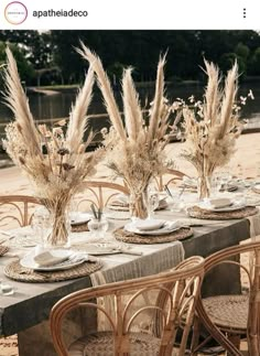 an outdoor table set with plates and vases filled with dried flowers on top of it