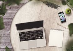 an open laptop computer sitting on top of a wooden table next to a notepad