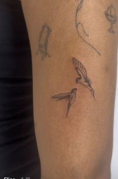 a woman's arm with two birds on it and one bird flying in the air