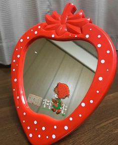 a red heart shaped mirror with a cartoon character on it