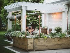 an outdoor dining area with wooden planters and string lights