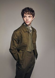 a young man in a green suit posing for the camera with his hands on his hips