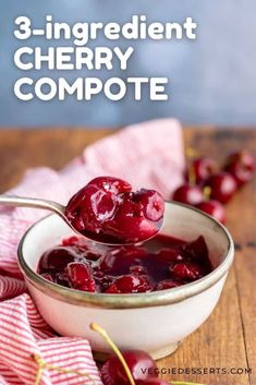 a spoon full of cherry compote on top of a wooden table with cherries