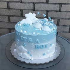 a blue and white cake sitting on top of a glass table next to a brick wall