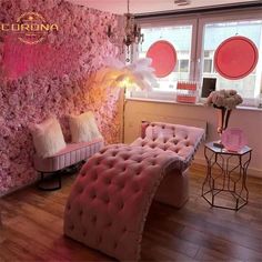 a living room with pink furniture and flowers on the wall next to a large window