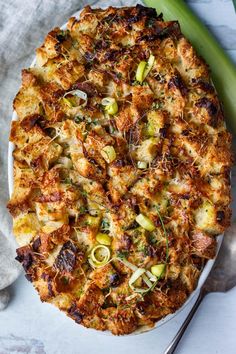 a white plate topped with a pizza covered in cheese and veggies next to a fork