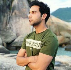 a man standing with his arms crossed in front of some rocks