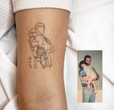 a man holding a baby in his arms with a tattoo on it's arm