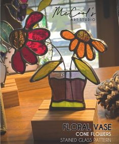 a stained glass flower vase sitting on top of a wooden table