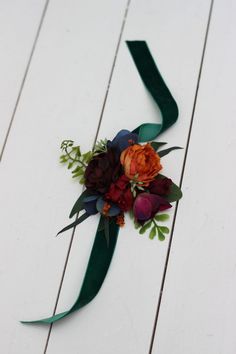 a bouquet of flowers is tied to a green ribbon on a white wooden surface with wood planks