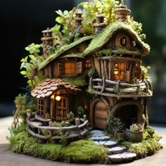 a small house made out of wood and moss with lights in the windows on top