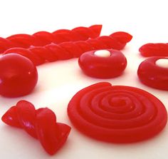 there are some red candies on top of the white tablecloth and one is in the shape of a spiral