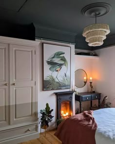 a bedroom with a bed, fireplace and painting hanging on the wall next to it