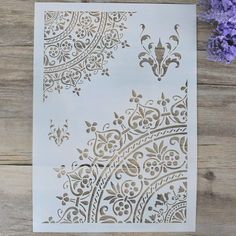 a white card with gold foil on it next to purple flowers