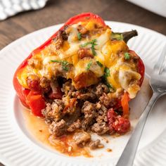 a close up of a plate of food with meat and cheese on the top, next to a fork