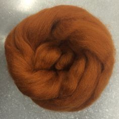 an orange colored wool roving sitting on top of a white countertop next to a gray floor