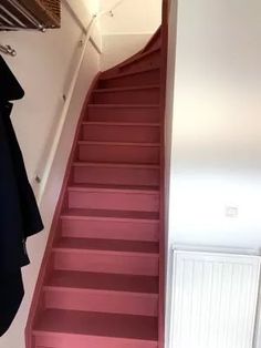 there is a red staircase leading up to the second floor with clothes hanging on it