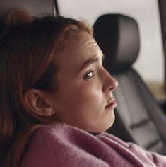 a woman sitting in the back seat of a car with her head turned to the side