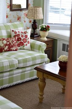 a green and white striped couch in a living room with flowers on the wall behind it