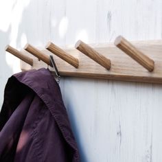 the coat rack is made out of wood and has four wooden pegs attached to it