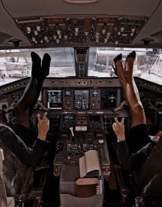 two people sitting in the cockpit of an airplane with their feet up on the ground