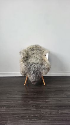 a chair made out of sheepskin with wooden legs in front of a white wall